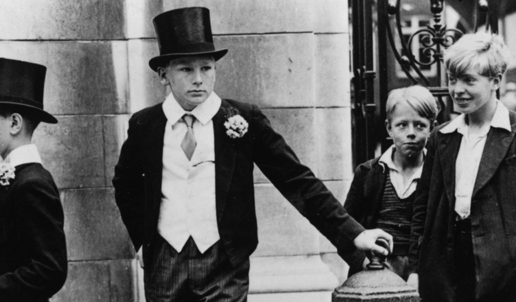 "Toff and Toughs" - 1937 photograph of five English boys: two dressed in the Harrow School uniform including waistcoat, top hat, and cane; and three nearby wearing the clothes of pre-war working class youths